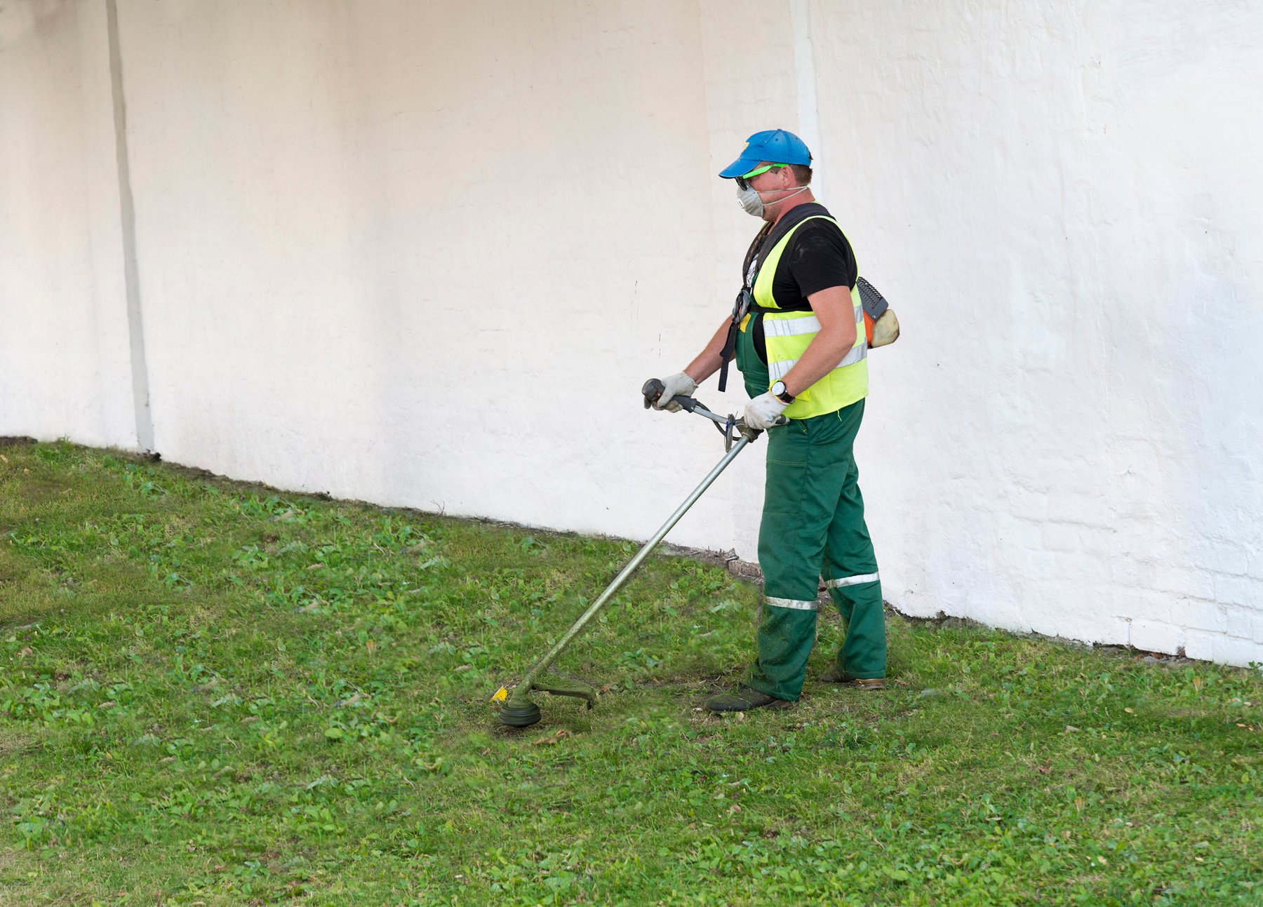 A man mows the grass with a lawn mower.